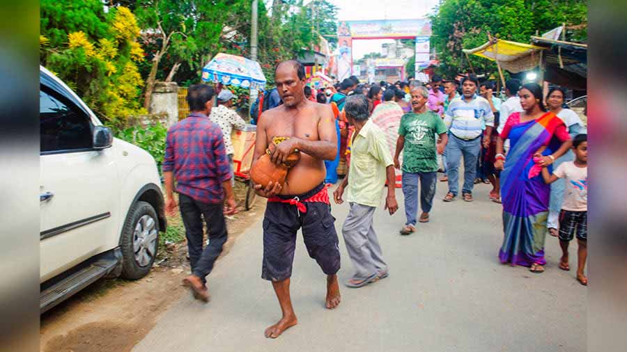 A devotee walks home with the loot of bhog in earthen pot 
