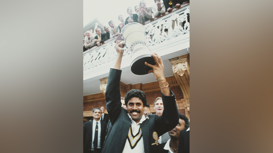 Team India captain Kapil Dev lifts the trophy on the balcony of the pavillion as Sunil Gavaskar (obscured right) looks on after the 1983 World Cup Final victory against West Indies at Lords on June 25, 1983 in London