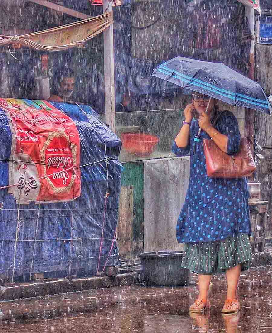 A young woman waits for transport at Gariahat crossing in torrential rain