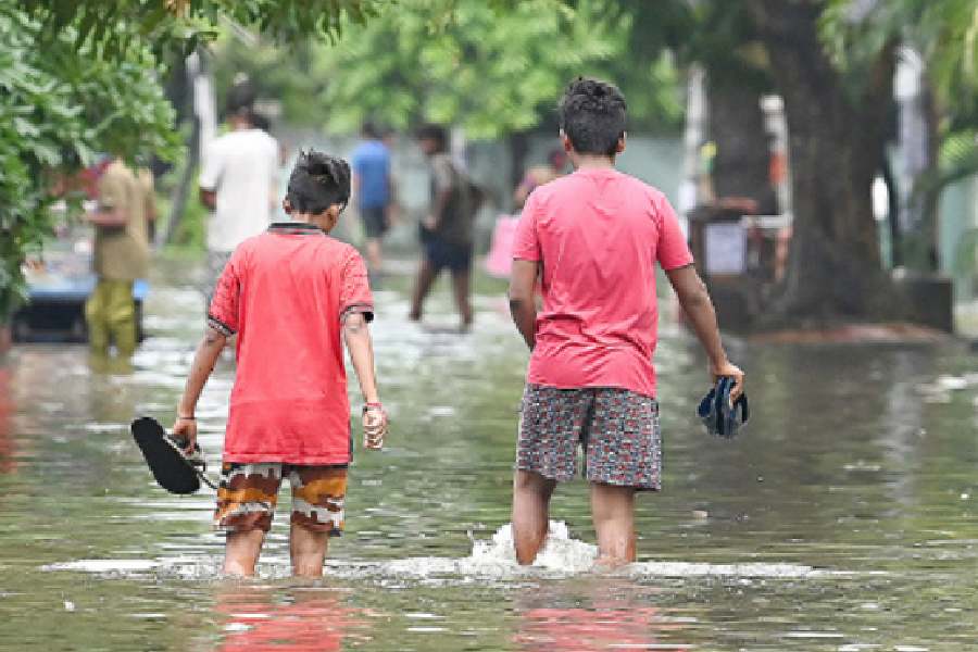 Boys wade through a waterlogged road near the floating market in Patuli on Wednesday