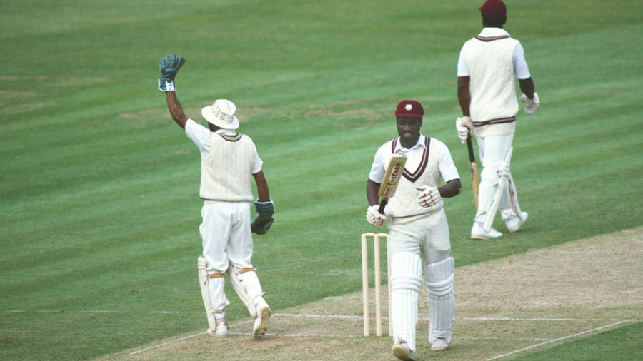 West Indies batsman Viv Richards leaves the field after being dismissed for 33 runs, caught by Kapil Dev (not pictured) off the bowling of Madan Lal (not pictured) as India wicketkeeper Syed Kirmani celebrates during the 1983 Cricket World Cup final Match between India and West Indies