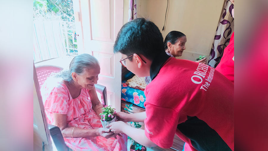 A student gifts a potted plant to a Sandhya Mita resident