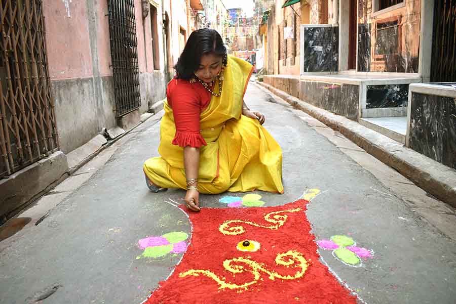 A woman in north Kolkata makes a rangoli with 'gulaal' on the road 