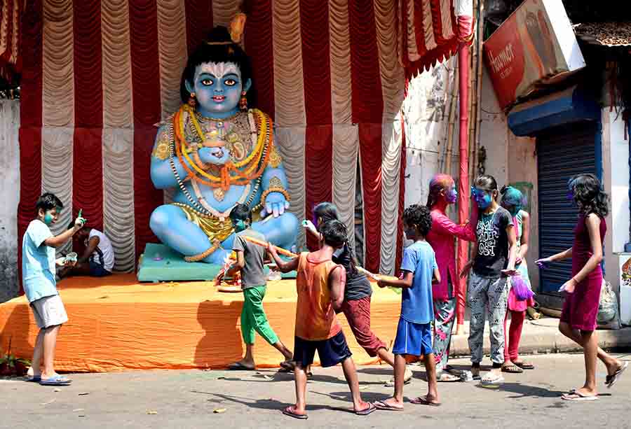 Children play with colours in front of a huge garlanded idol of Gopal in north Kolkata