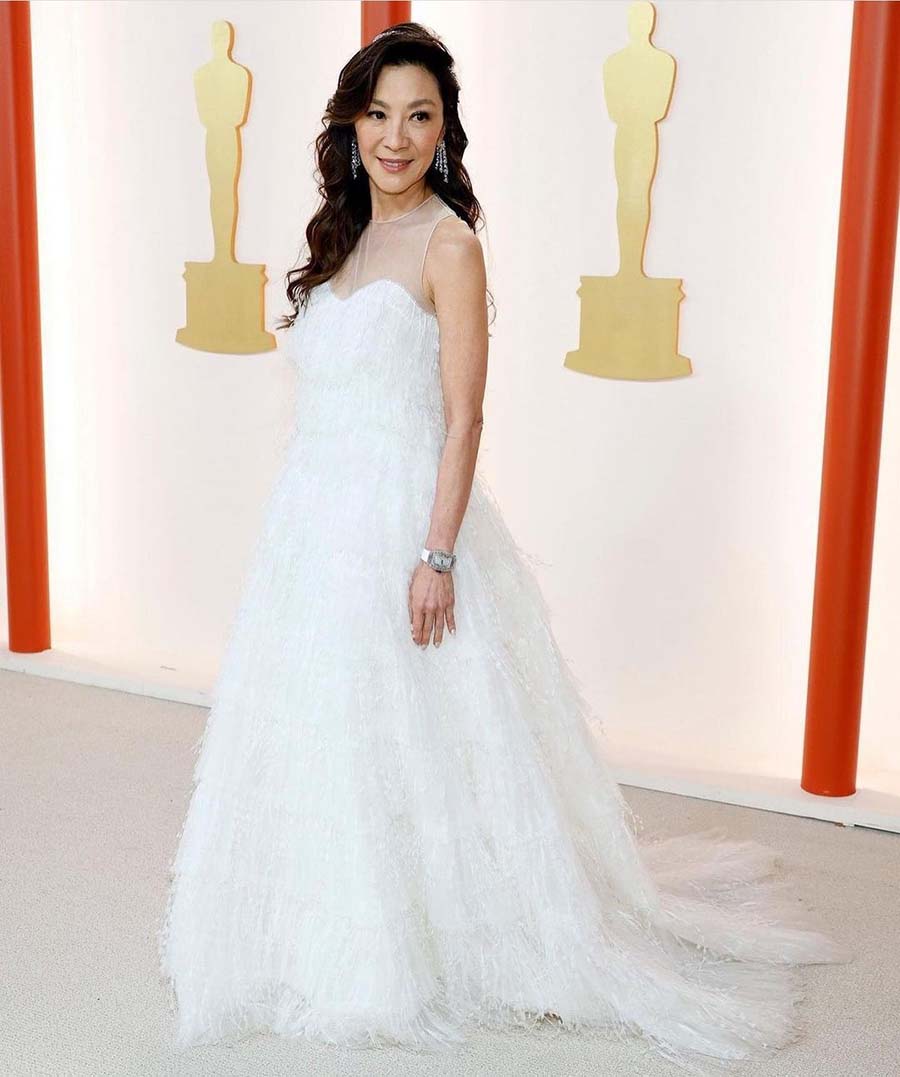 Oscar winner Michelle Yeoh dazzled in a hand-sewn feathery Dior gown with a sheer neckline and diamond earrings by Moussaieff. 