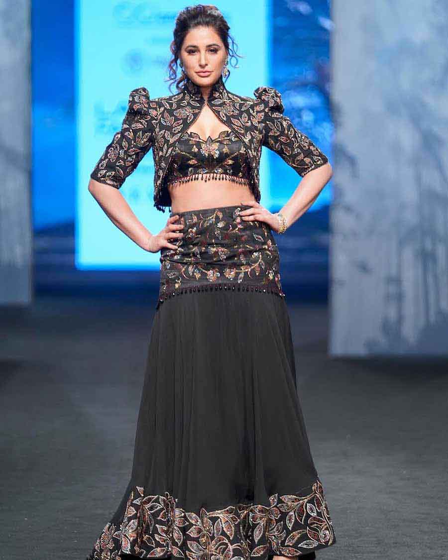Nargis Fakhri walked the ramp in a Sejal Kamdar ensemble — a black lehenga with floral print and a high-neck pointed-shoulder jacket. 