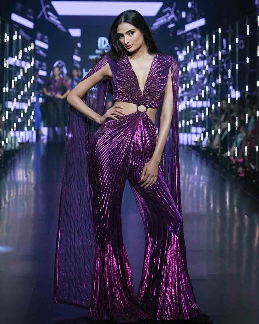 Athiya Shetty brought out her supermodel walk for Namrata Joshipura in a cut-out purple shimmery flared jumpsuit with a caped back inspired by post-modern disco ensembles. 
