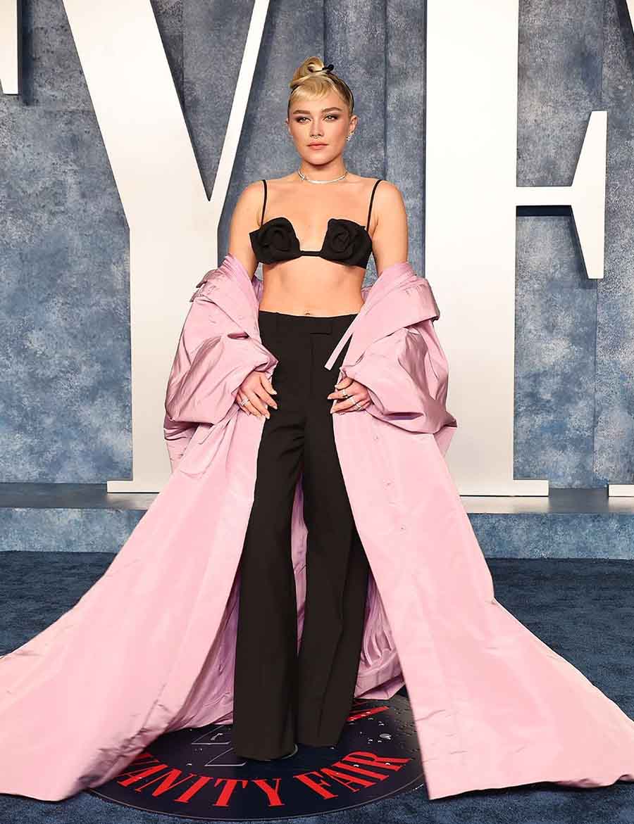 Florence Pugh went for another Maison Valentino look. She opted for a rose-adorned bralette paired with black trousers and a pink cape coat. 