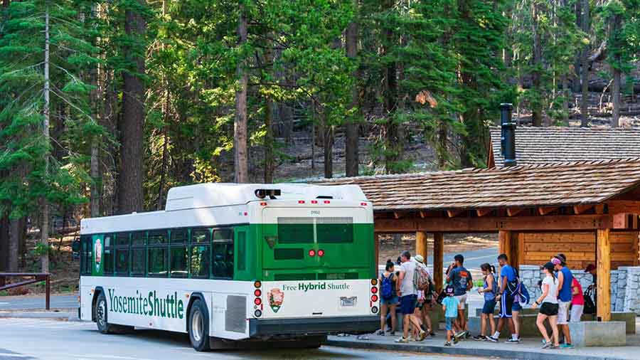Tourists board a bus to the park from Mariposa 