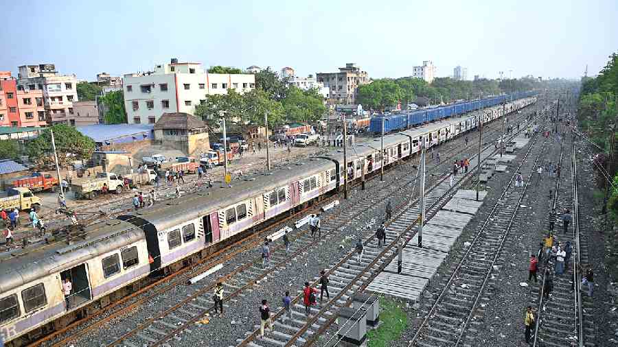 Commuters walk along railway tracks near Ballygunge station after train services were suspended