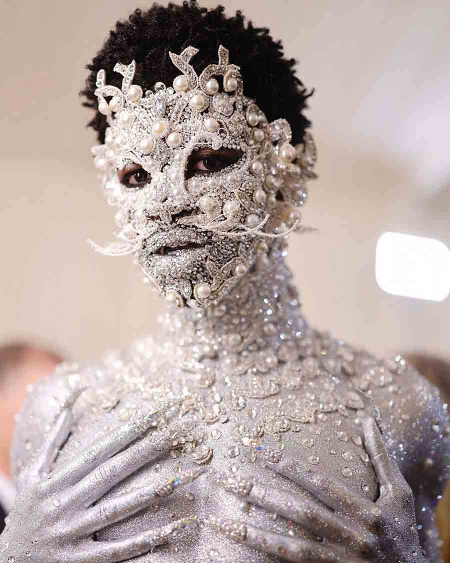 Lil Nas X made a statement in a silver Dior thong and painted his entire body ivory. The Rapper-singer also embellished his body with pearls and crystals. 
