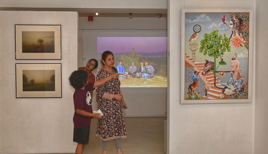 Artist Bikash Bhattacharjee’s daughter and granddaughter at the exhibition. Seen in front right is The Green Light, an oil-on-acrylic work by Suraj Kumar Kashi, an artist from Bihar. On the left is the Dawn Series, prints on archival paper by Buku Sarkar
