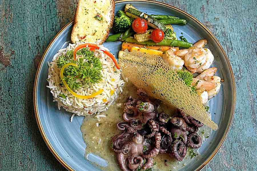 Grilled Octopus with Garlic Prawn is an European platter with grilled octopus in pesto mayo sauce, veggies sautéed in balsamic vinegar and served with rice pilaf.