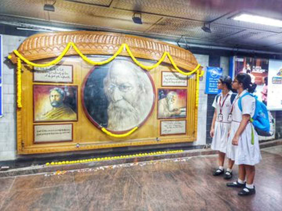 Two young commuters admire the freshly garlanded mural of Rabindranath Tagore at Rabindra Sadan Metro station on Tuesday