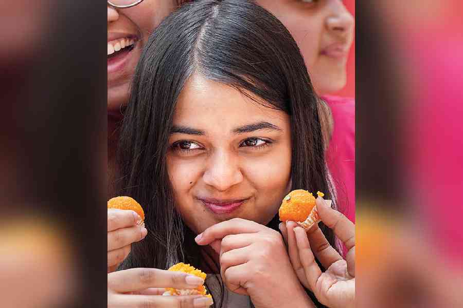 Tanvika Singh, who secured 99.25 per cent marks in CBSE Class XII exams, is offered sweets by friends in New Delhi on Friday.