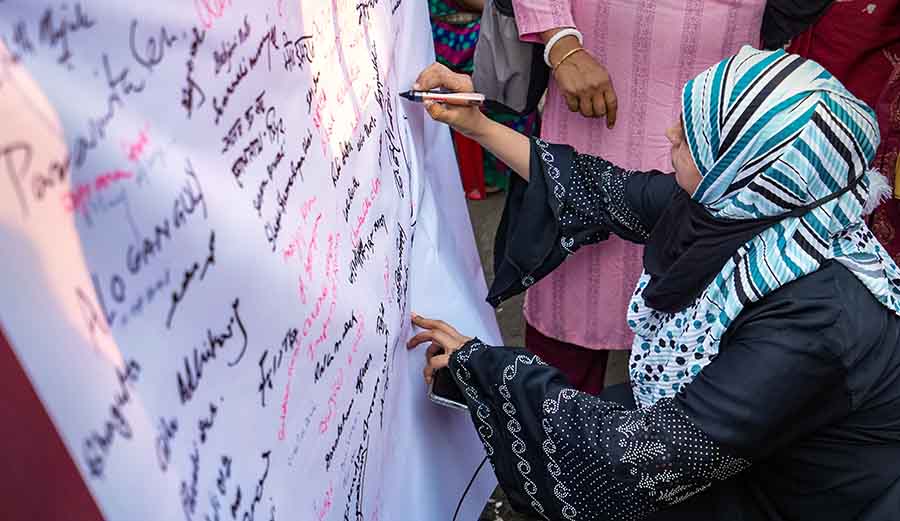 A pedestrian signs on a large piece of paper on Monday during a mass signature campaign in Kolkata organised by the All India Democratic Women's Association (AIDWA) in support of women wrestlers protesting against the WFI chief Brij Bhushan Sharan Singh 