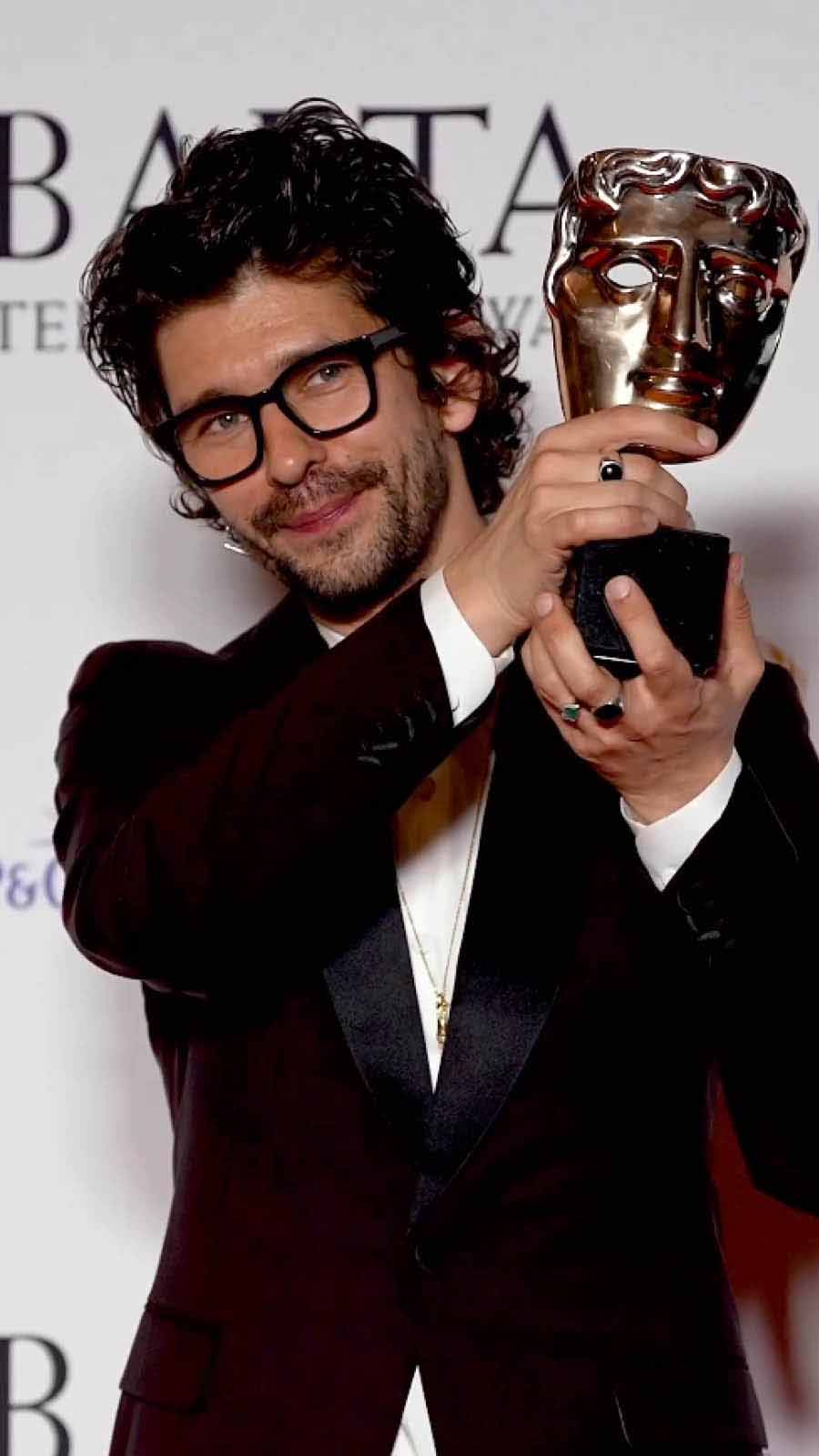 Ben Winshaw sported bold-framed glasses with a black suit as he posed with his trophy for Best Leading Actor, which he won for his role in This is Going to Hurt.
