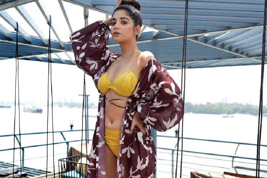 Bitasta sports a floral-printed cotton bright yellow bikini, styled with a complementing brown-and-white satin jacket designed with flowy bishop sleeves. The yellow printed fabric used as a hair tie and matching yellow stilettos complete the look.