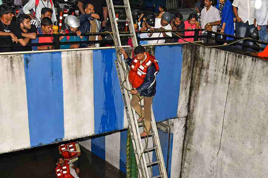 Rescue operations under way after the car got stuck in the waterlogged underpass following heavy rain in Bangalore on Sunday.