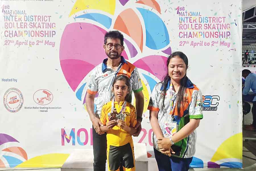 Vidushi Agarwal holds up her medals, flanked by officials 