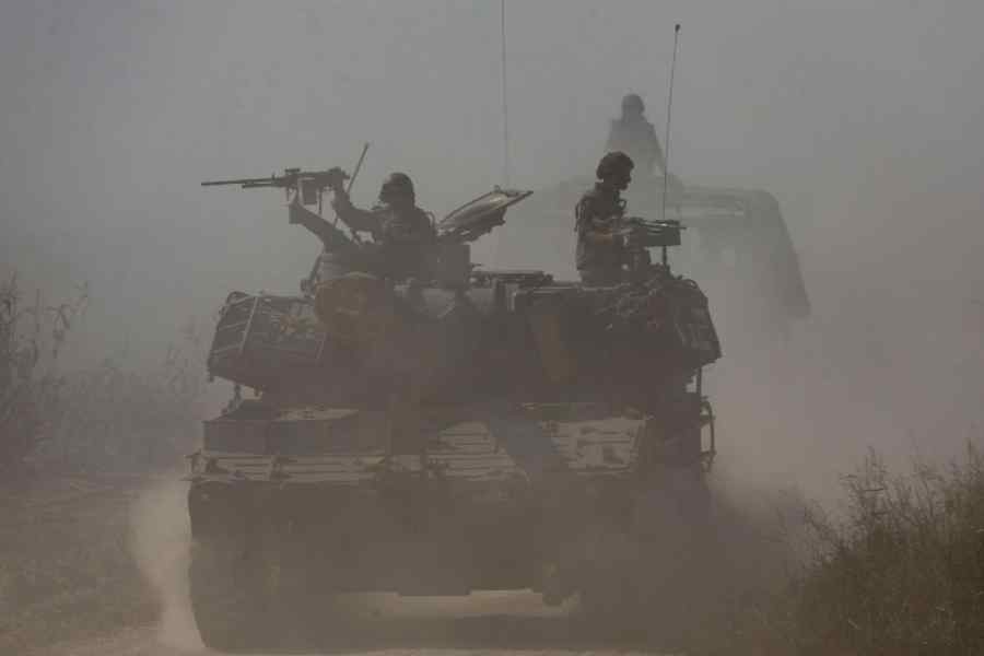 Israeli soldiers ride atop an artillery unit near the Israeli side of the border between Israel and the Gaza Strip.