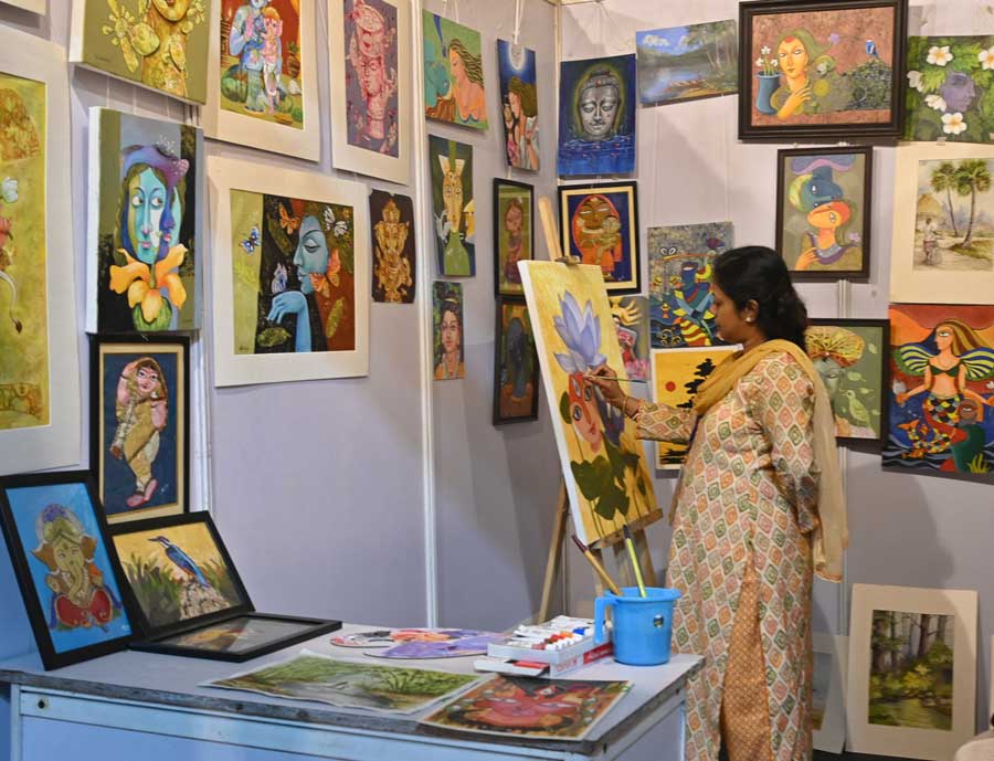 An artist paints on a canvas at her stall