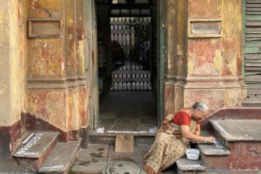 Ratnabali Ghosh paints alpana outside a house in Bowbazar on Thursday