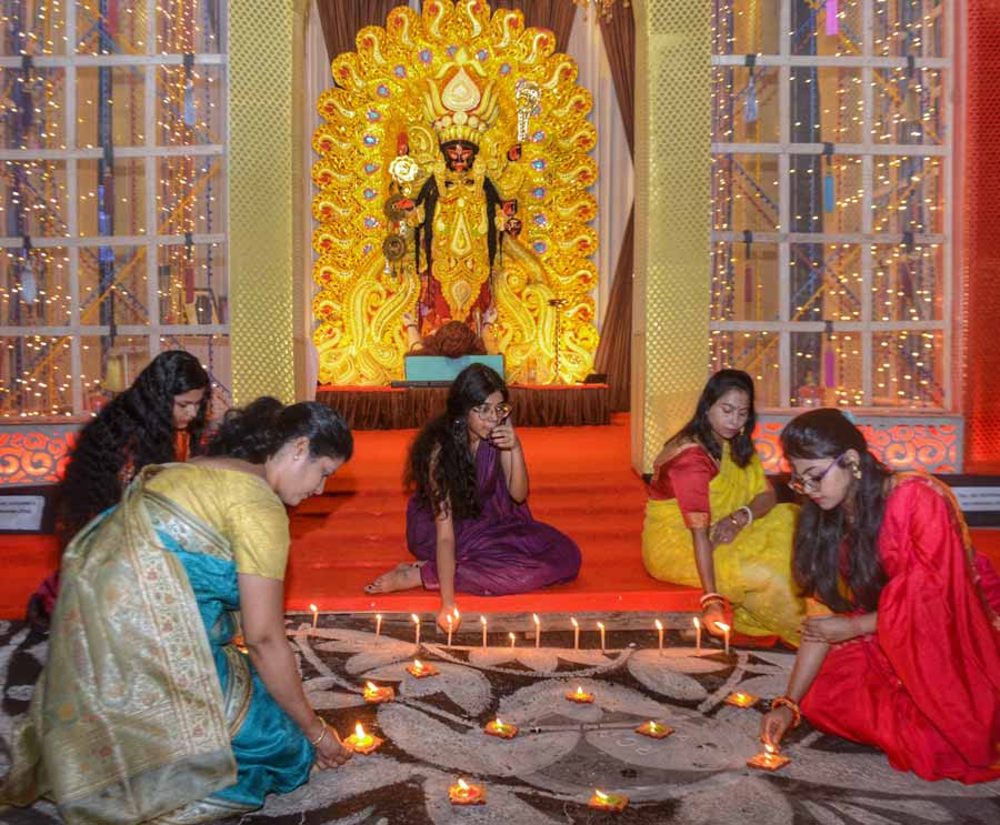 Women light diyas and candles at a Kali Puja pandal on Sunday evening
