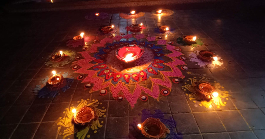 A rangoli made up of dry colours and lit up with terracotta diyas at a Kolkatan’s home