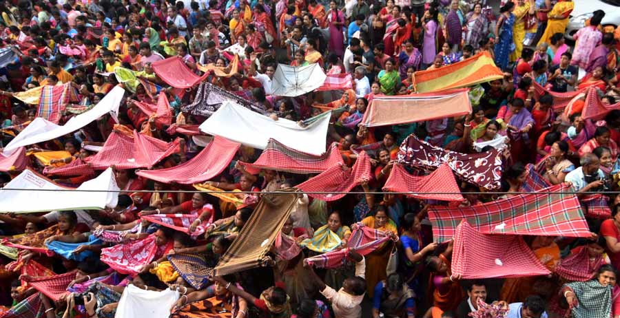 Mostly women devotees jostle with each other as they spread out ‘gamchhas’ to catch the rice thrown from the balcony above at Madan Mohantola