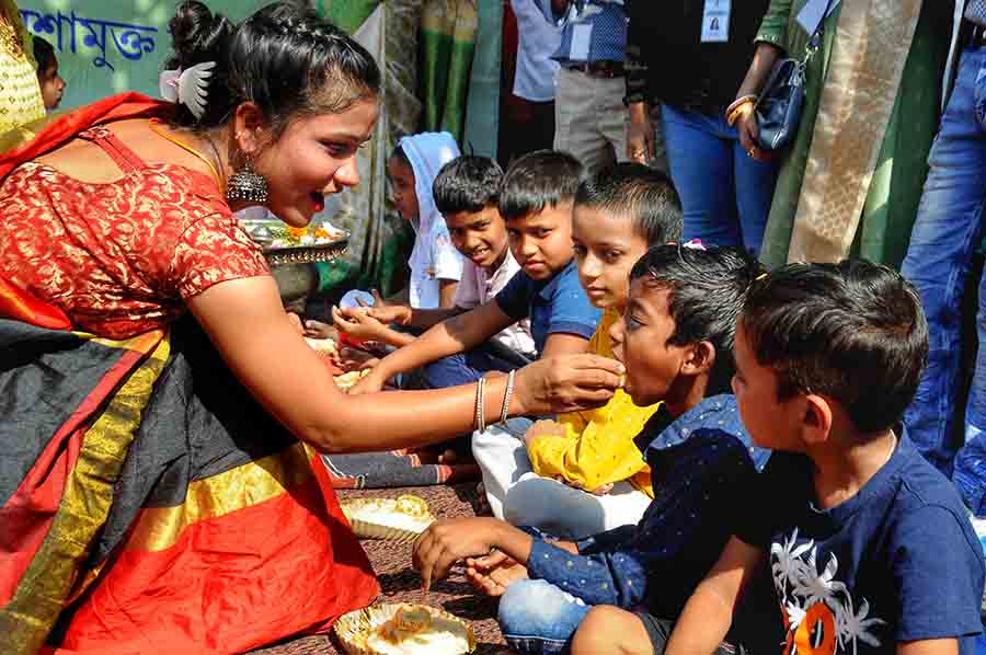 A girl treats an underprivileged child to a ‘mishti’ near Sovabazar Metro station on the occasion of Bhai Phonta on Wednesday