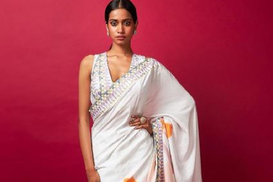 This silk sari with a floral print lends an elegant look. It has been paired with a geometric printed sequinned blouse.