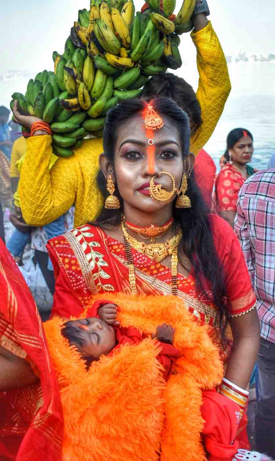 A devotee cradles her baby wrapped in woollens at a north Kolkata ghat on Monday morning