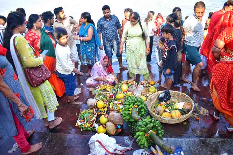 After an entire night at the ghat, devotees wait beside large hands of bananas and other puja paraphernalia before returning to their homes on Monday morning