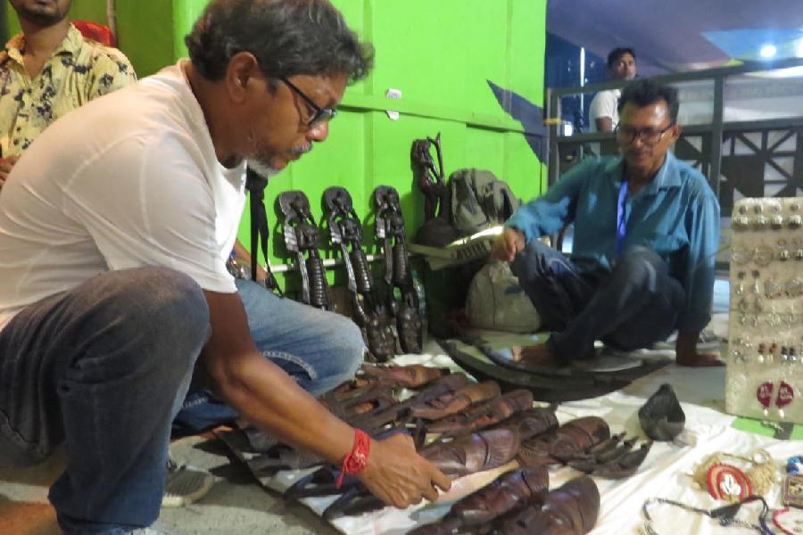 Artist Subal Pal takes a pick of wooden masks from a South Dinajpur artist at Sonajhuri Haat in New Town. 
