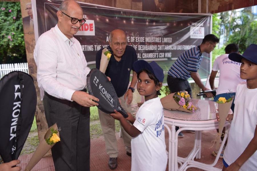 Exide Industries CEO Subir Chakraborty gifts a racquet to one of the children from the foundation as Jaidip Mukerjea looks on