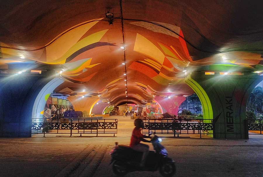 Under the Metro rail bridge in New Town, the stage is set for several stalls to be opened. The pillars and walls have been painted with graffiti and illuminated with lights 