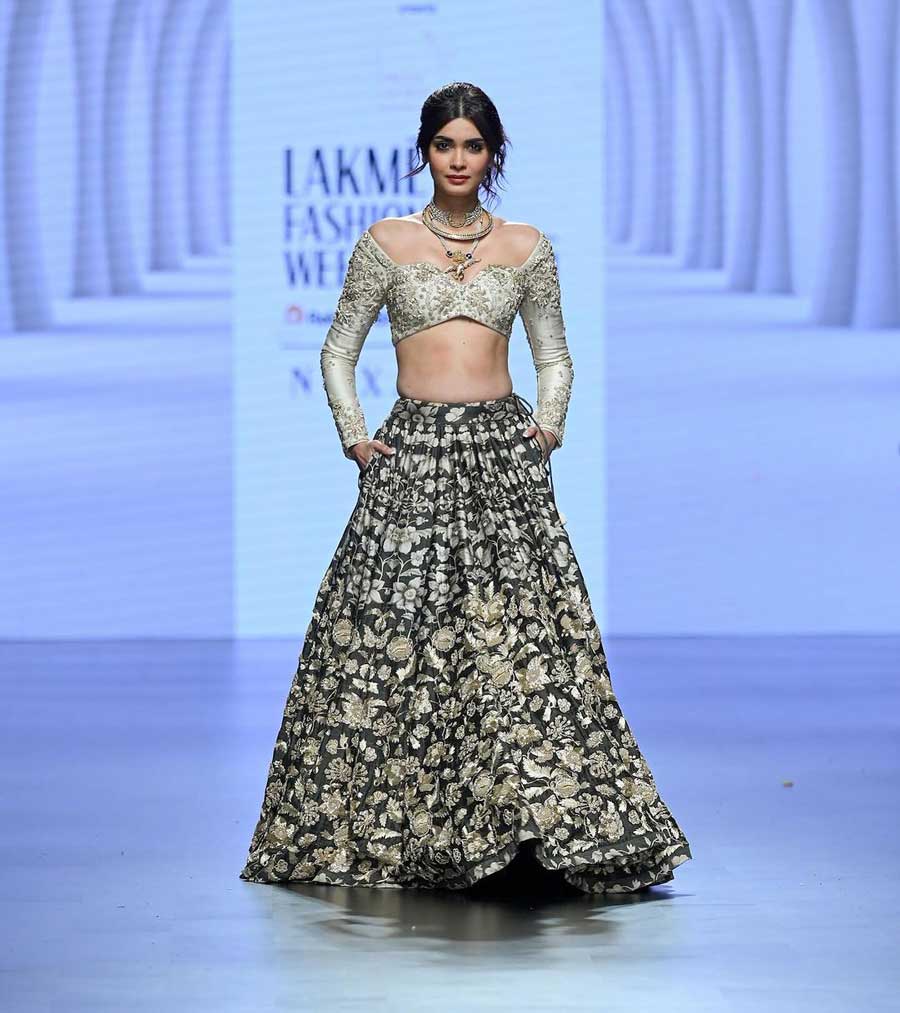 Diana Penty presented Paulmi and Harsh’s off-shoulder blouse with a plunging neckline and golden embroidery from their ‘Rooh’ collection. She paired it with a black skirt that had beige floral prints all over.