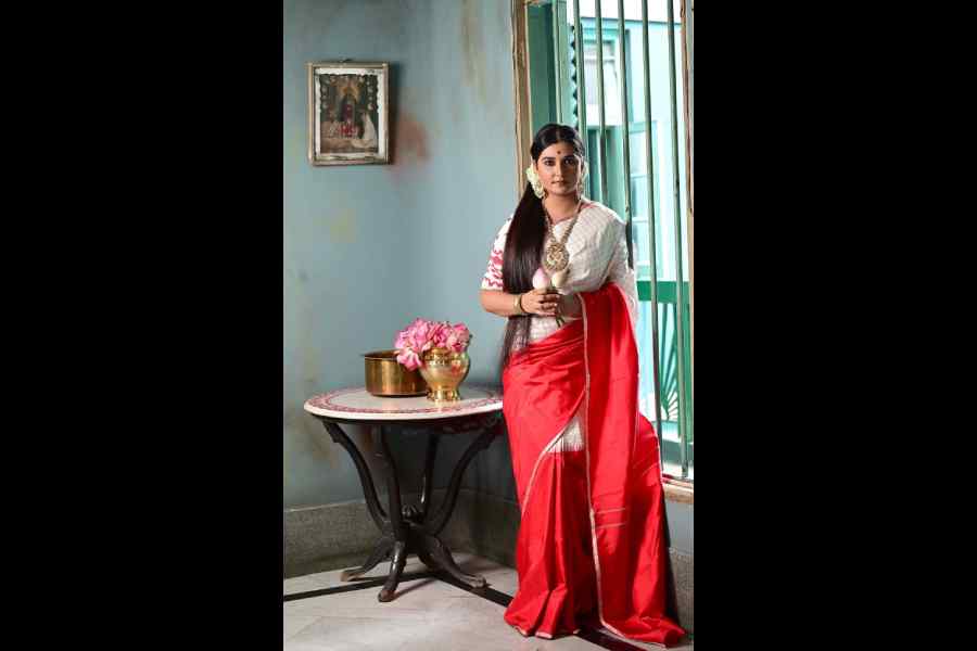 Somlata’s red-and-white sari in this frame is a confluence of a traditional weave with a contemporary design. This Kanjeevaram designed with smart checks is colourblocked with the bright solid red and temple-motif border. It is paired with a traditional Dhakai blouse. Natural make-up, vermilion bindi, statement jewellery and fresh white flowers in the hair complete this statement look