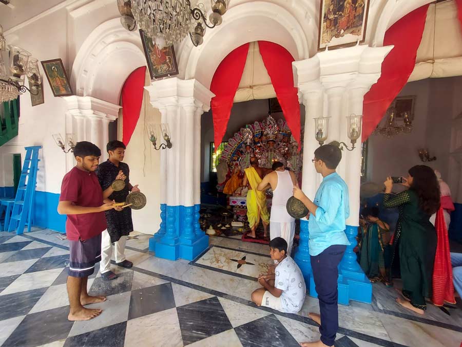 Family members play the kashor as the priest performs Saptami puja 