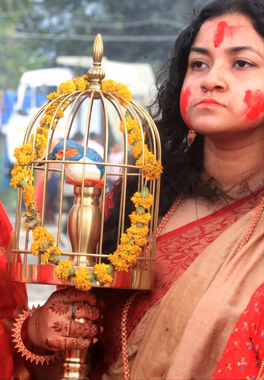 A woman holding a figurine of a ‘Neelkanth’ bird. The ritual of releasing a ‘Neelkanth’ bird before Durga’s ‘bisarjan’ was followed back in time. It is believed to bring fortune and good luck to the family  