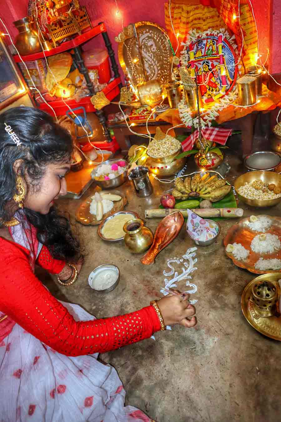 A young woman applies ‘alpona’ in front of goddess Lakshmi in Kolkata