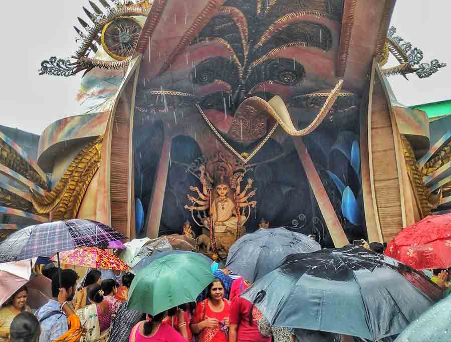 Intermittent showers on Navami could do little to dampen the enthusiasm of [andal-hoppers. Ot came umbrellas and they marched on. In picture, Chetla Agrani  
