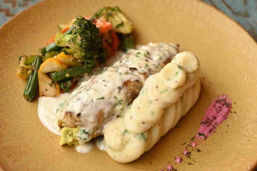 Grilled Chicken with Cheese Sauce: Perfectly grilled whole chicken stuffed with a creamy cheesy mix, this entree is served along with sautéed veggies