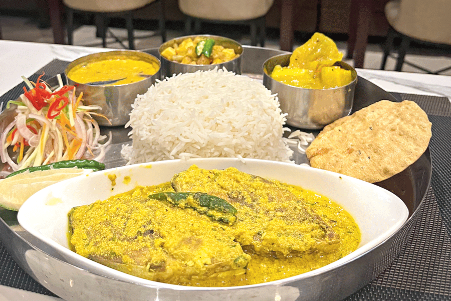 A hilsa dish comes with rice, alu posto, bhaja moong daal and chutney.
