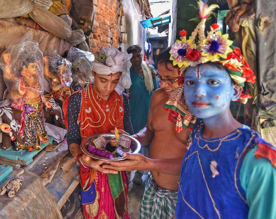 An artist on Kumartuli donates to a Nandadulal dancer. The performer, dressed as Lord Krishna, carrying a bowl had a Gopal in it