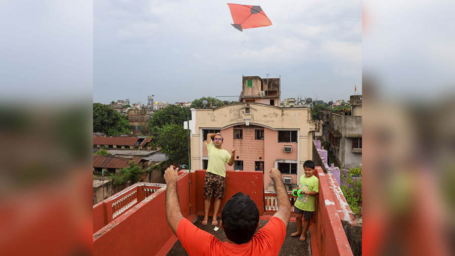 A family launches a kite from their terrace, in Kolkata
