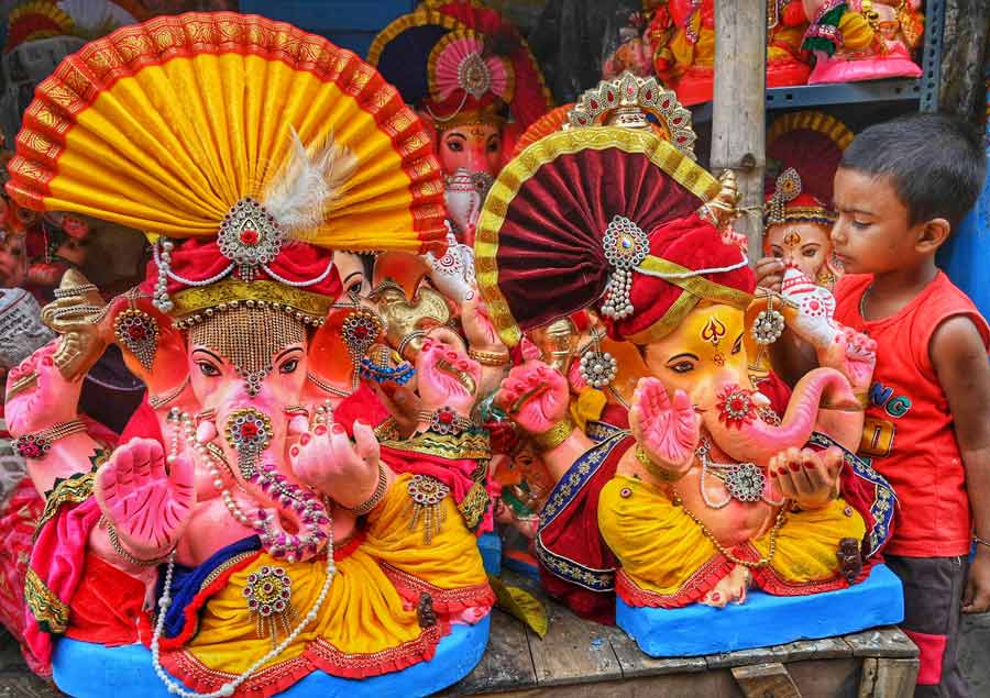 A young boy seems intrigued by the embellishments adorning statues of Lord Ganesh on sale  