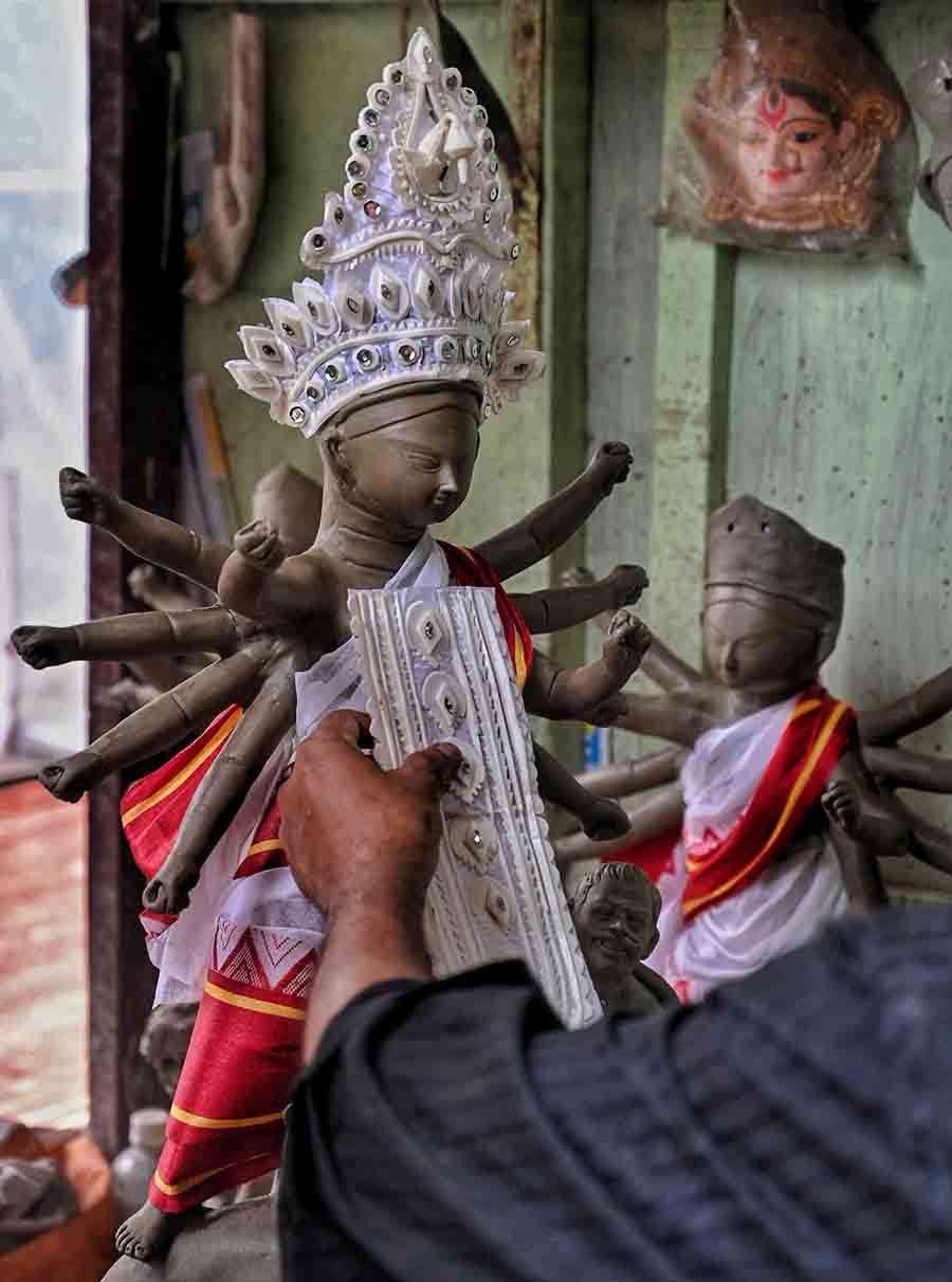 An artist gives finishing touches to miniature Durga idols at Kumartuli 