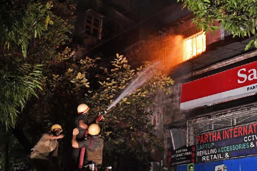 Firefighters spray water on the second floor of the building in Chandni Chowk where a fire broke out on Sunday evening